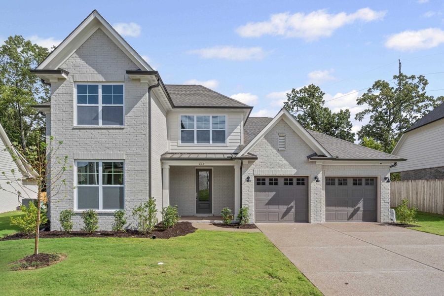 View of front of home featuring an attached garage, a standing seam roof, brick siding, concrete driveway, and roof with shingles
