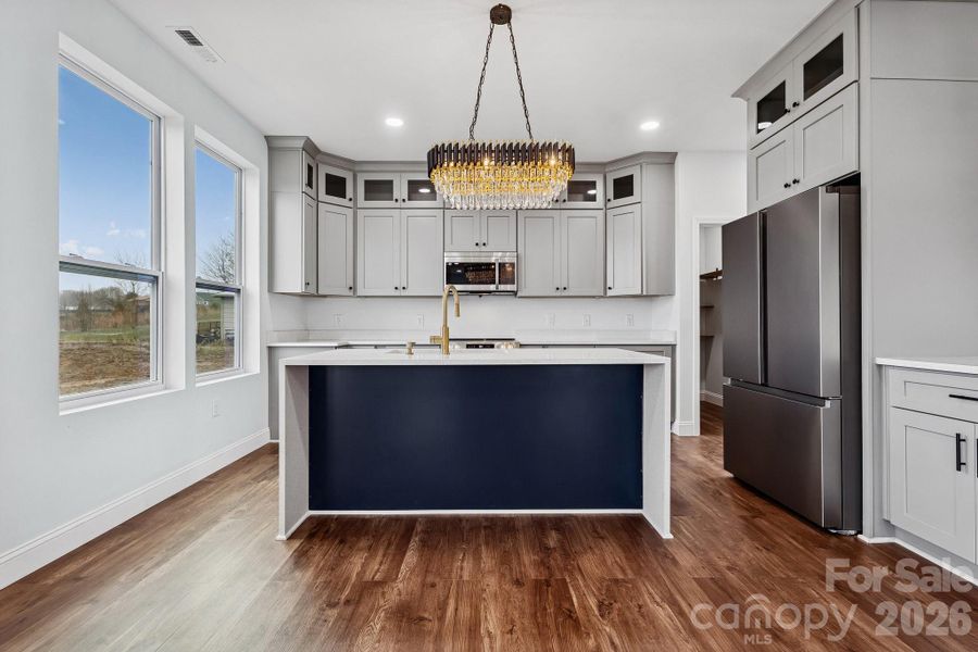 gorgeous kitchen area provides all of the stainless appliances needed for everyday cooking, large counter spacing, stacked cabinetry, elegant lighting and a waterfall quartz counter top island