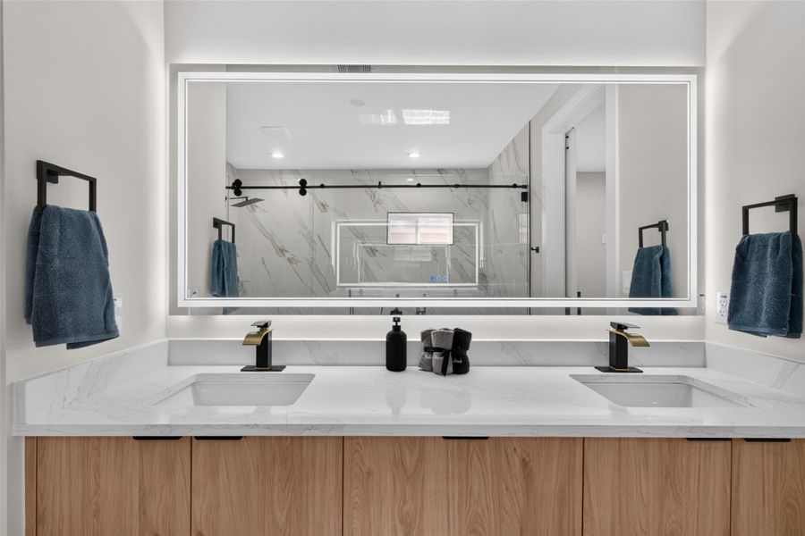 Elegant dual-sink bathroom with a sleek, backlit mirror and modern fixtures, complemented by a spacious, marble-accented shower area.