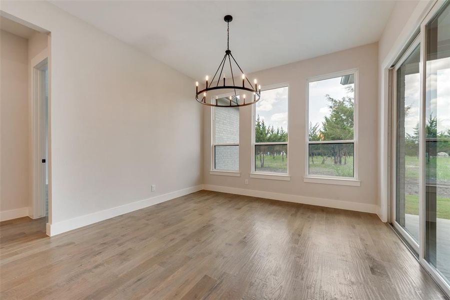 Unfurnished dining area with a healthy amount of sunlight, an inviting chandelier, and hardwood / wood-style floors