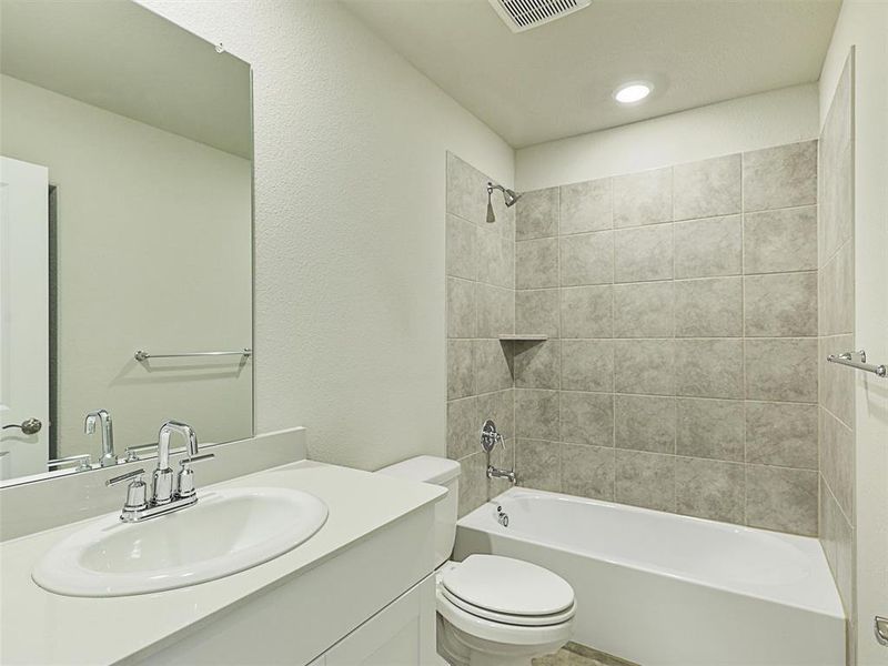 Full bathroom with tiled shower / bath combo, toilet, and vanity