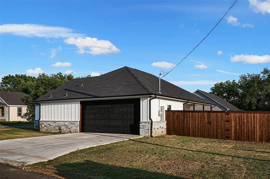 View of side entry garage and privacy fence.