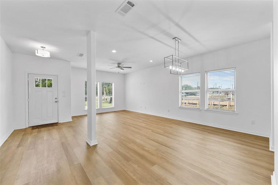 Spacious interior featuring wood-finish flooring, white walls, and multiple windows with blinds