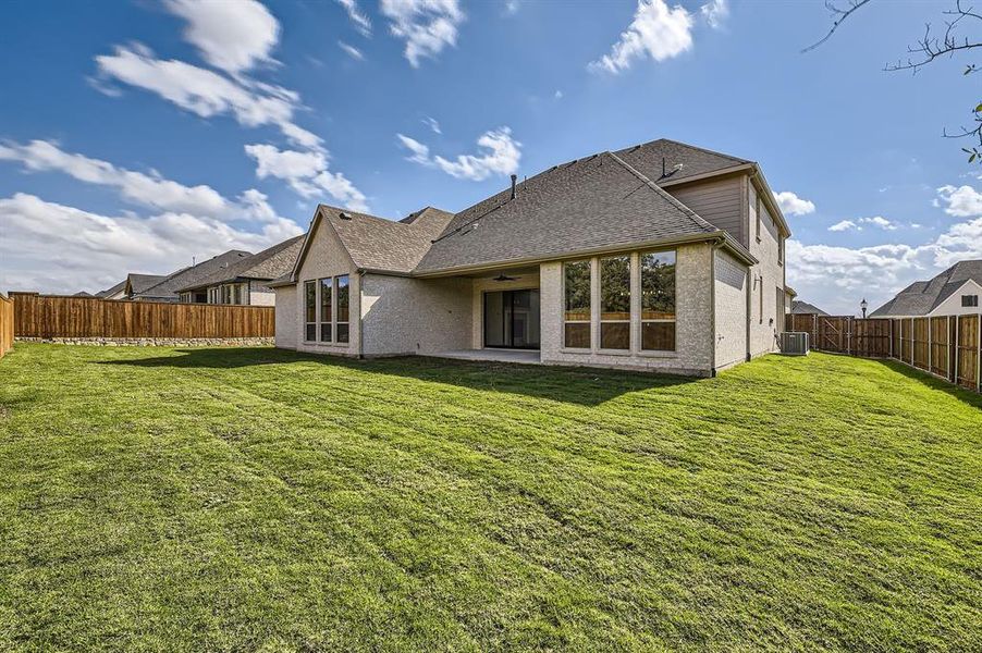 Rear view of house with a lawn and cooling unit