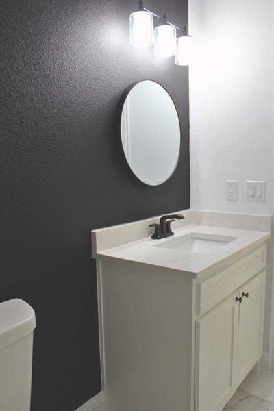 Half bath with vanity and light marble finish floors Half bath with vanity and light marble finish floors