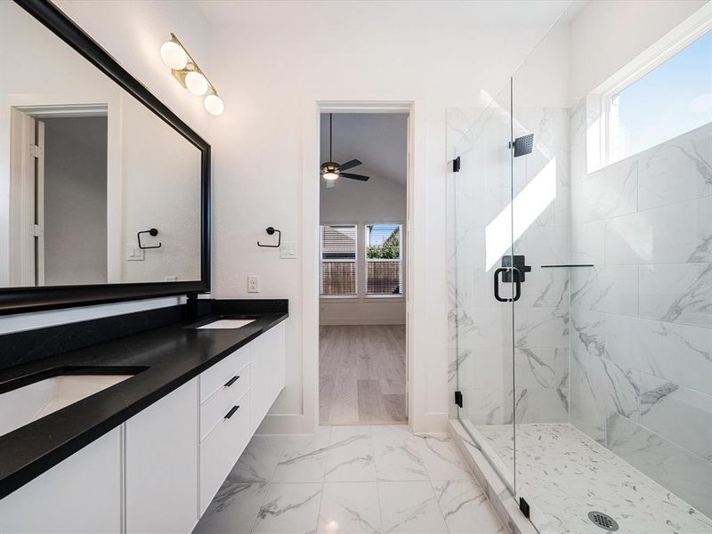 Full bathroom with a marble finish shower, double vanity, light marble finish flooring, and a ceiling fan