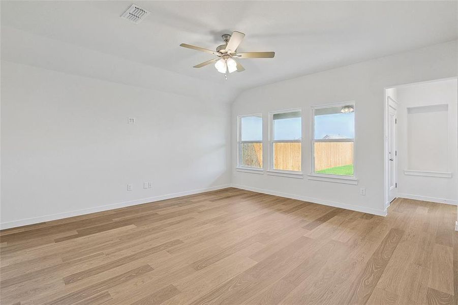 Spare room with vaulted ceiling, ceiling fan, and light hardwood / wood-style floors