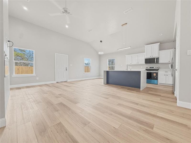 Unfurnished living room with ceiling fan, lofted ceiling, light wood-type flooring, and recessed lighting