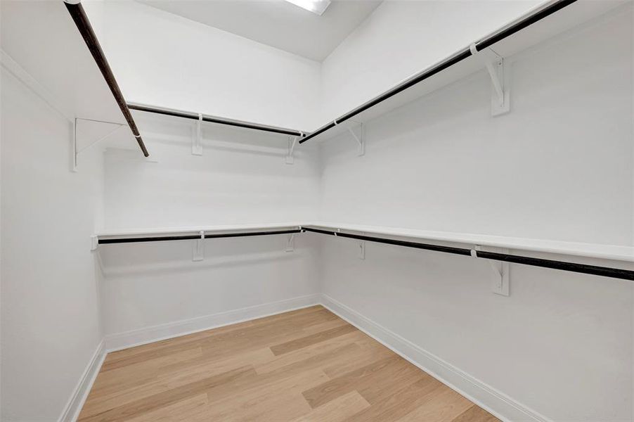 Walk in closet with light wood-style flooring Walk in closet with light wood-style flooring