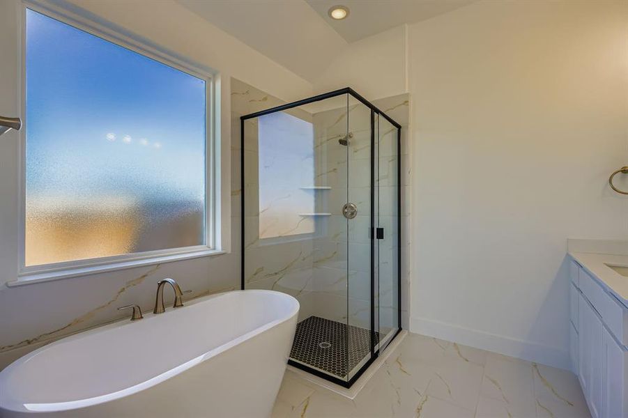 Bathroom with marble look tiles, a soaking tub, a marble finish shower, and vanity