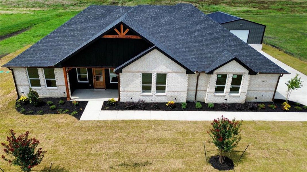 View of front facade featuring brick siding, a front lawn, and a shingled roof