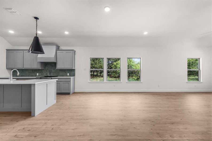 Kitchen featuring gray cabinetry, backsplash, light floors, recessed lighting, and premium range hood
