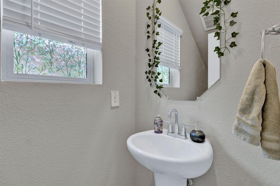 The property features a pedestal sink with a chrome faucet, a wall-mounted mirror, and a towel ring with a towel