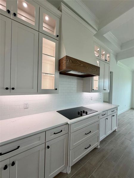 Modern kitchen featuring white shaker cabinetry with dark hardware, white subway tile backsplash, and light-toned countertops