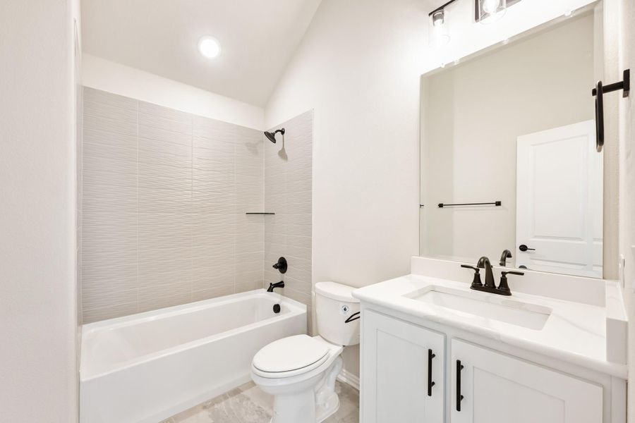 Bathroom with white vanity, tub-shower combo with tile surround, and black hardware fixtures Bathroom with white vanity, tub-shower combo with tile surround, and black hardware fixtures