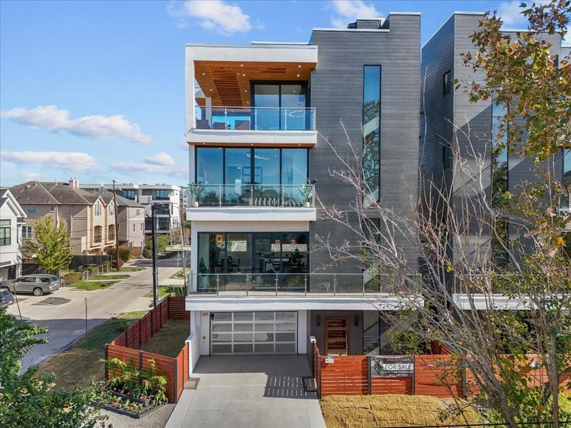 Modern three-story townhouse with sleek, dark exterior and large glass windows. Features spacious balconies and a covered garage. Situated on a corner lot with a fenced yard, in a residential neighborhood. Modern three-story townhouse with sleek, dark exterior and large glass windows. Features spacious balconies and a covered garage. Situated on a corner lot with a fenced yard, in a residential neighborhood.