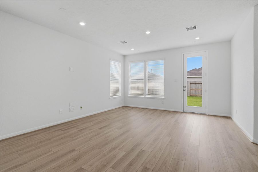 Bring family and friends together in this beautiful Great Room! It features soaring ceilings, recessed lighting, custom paint, vinyl plank flooring, large windows that fill the space with natural light, and a back access door that directly goes out to the patio and backyard green space!