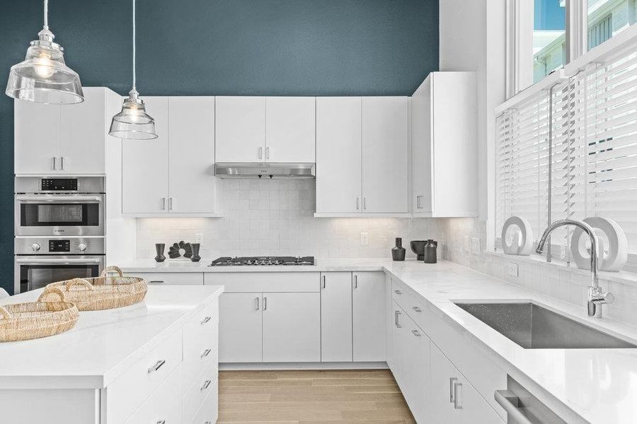 Kitchen with stainless steel appliances, white cabinetry, and light stone counters
