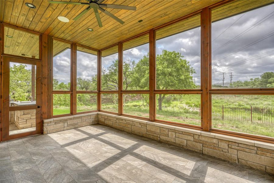 Unfurnished sunroom with wooden ceiling and stone tile flooring