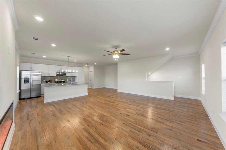 Unfurnished living room featuring light wood finished floors, ornamental molding, ceiling fan, and recessed lighting