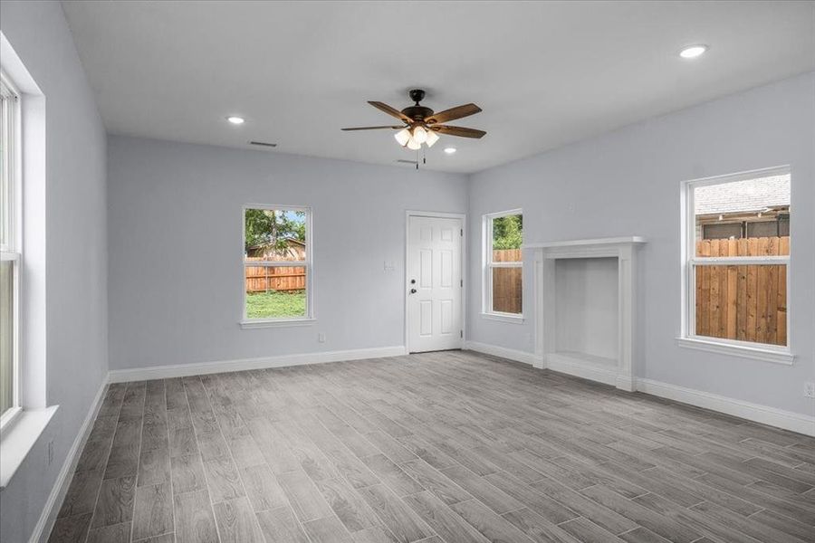 Unfurnished living room with wood finished floors, ceiling fan, plenty of natural light, and recessed lighting