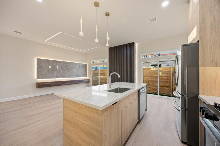 Kitchen featuring Quartz countertop, light brown cabinets, open floor plan, light wood finished floors, and modern cabinets