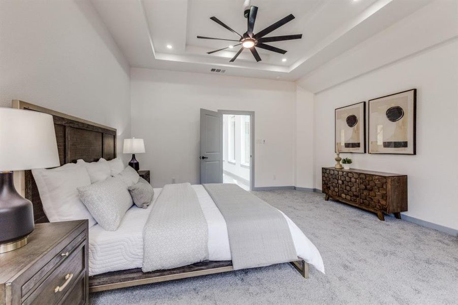 Bedroom featuring ceiling fan, light carpet, and a raised ceiling