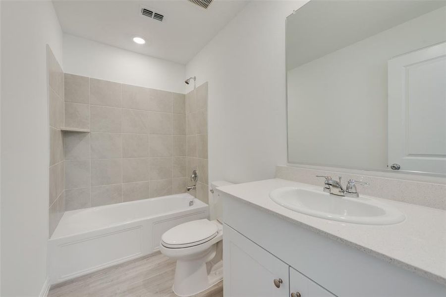 Full bathroom with toilet, hardwood / wood-style floors, vanity, and tiled shower / bath