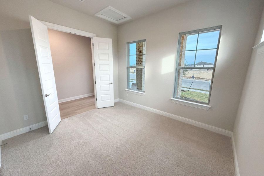 Unfurnished bedroom with attic access and light colored carpet