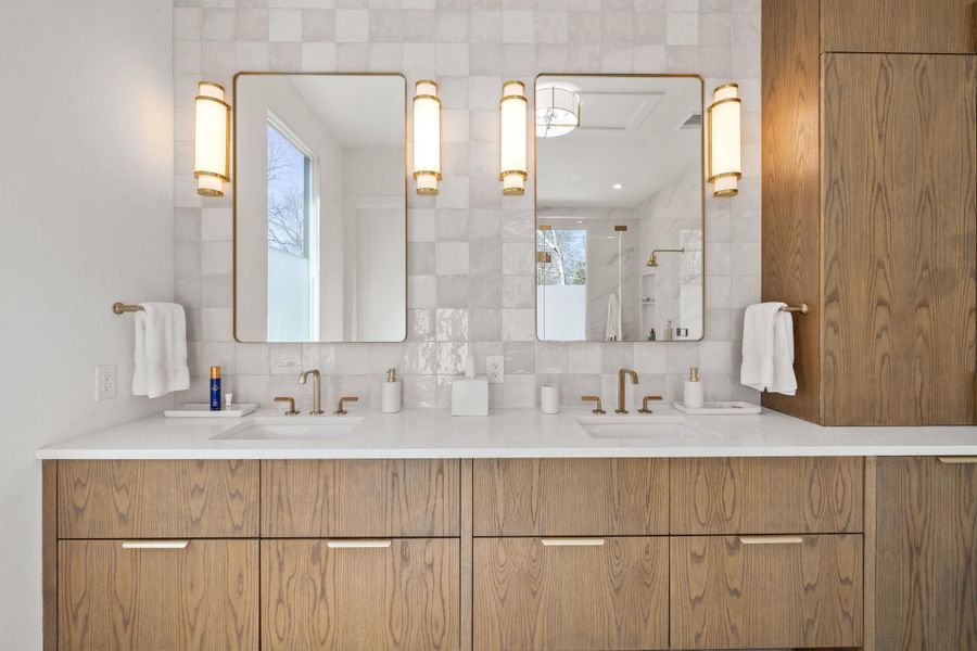 Bathroom featuring a shower stall, double vanity, and backsplash