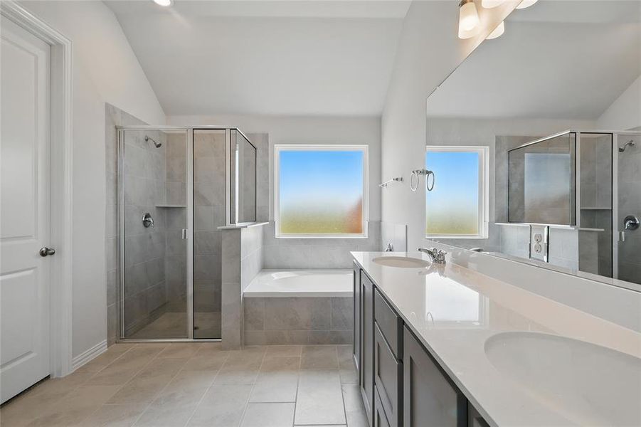 Bathroom with vaulted ceiling, double vanity, a garden tub, a shower stall, and light tile patterned floors Bathroom with vaulted ceiling, double vanity, a garden tub, a shower stall, and light tile patterned floors