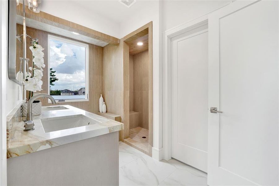 Primary bath with natural stone double-sink vanity, soaking tub with an amazing view, and a standing shower with custom tiles from floor to ceiling.