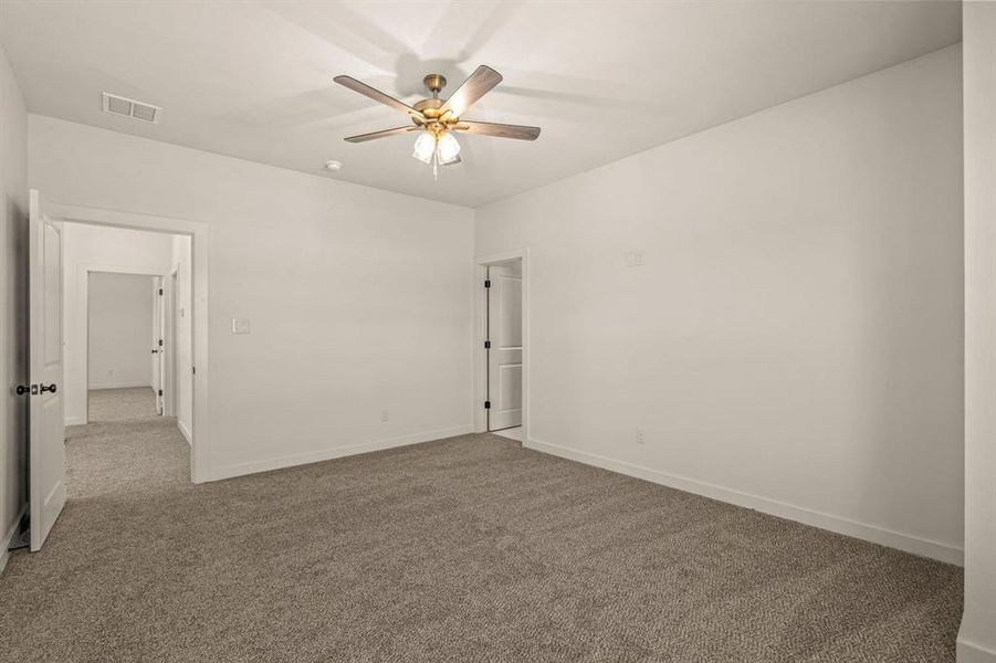 Carpeted empty room featuring ceiling fan and baseboards