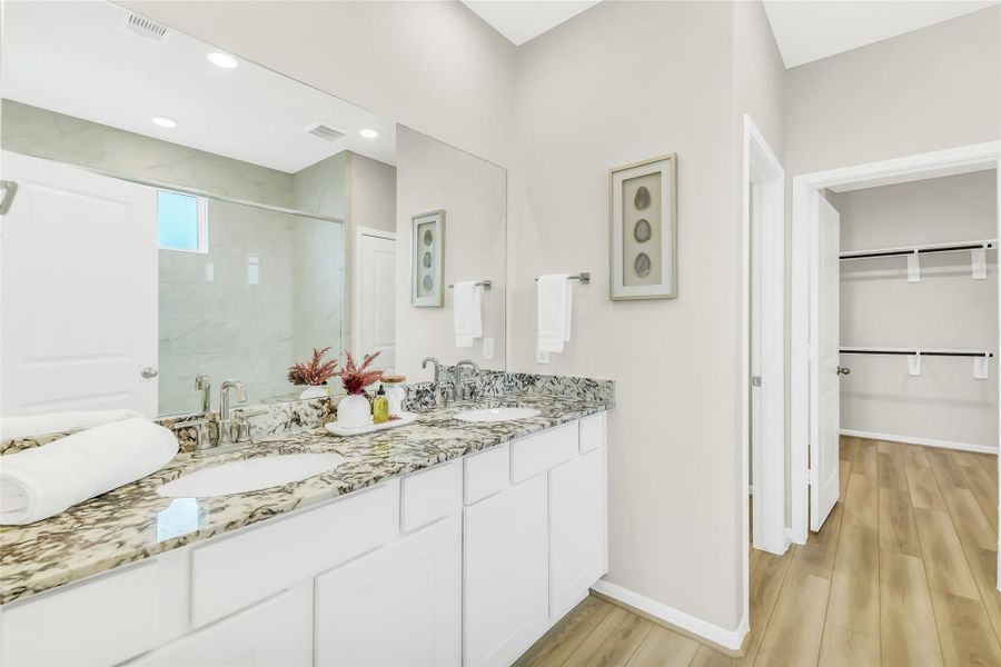Dual sinks and stone countertops offer ample space for daily routines, complemented by clean lines and modern lighting.