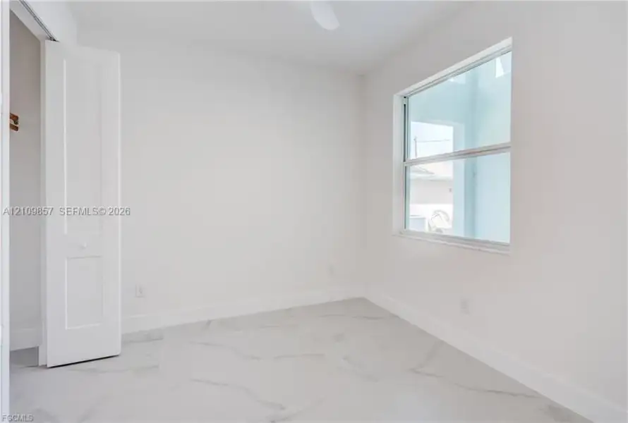 Room featuring large-format tile flooring, bright neutral walls, a single-hung window, and a built-in closet with double-panel doors
