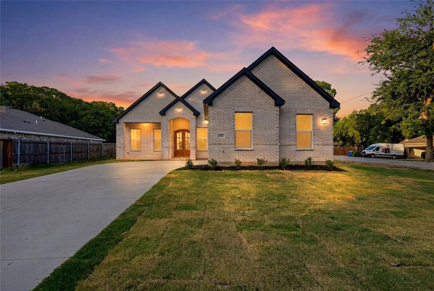 Light brick exterior with dark trim, featuring multiple gables and an arched entryway