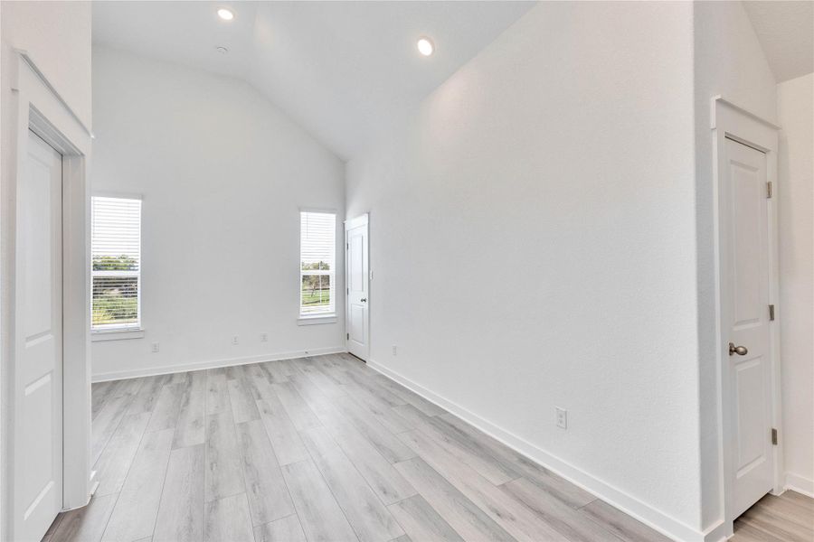 Unfurnished bedroom featuring light wood-style floors, recessed lighting, and high vaulted ceiling