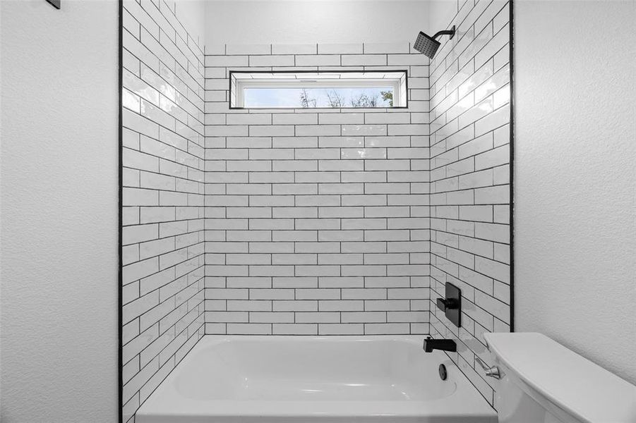 Full bath with a textured wall and bathing tub / shower combination