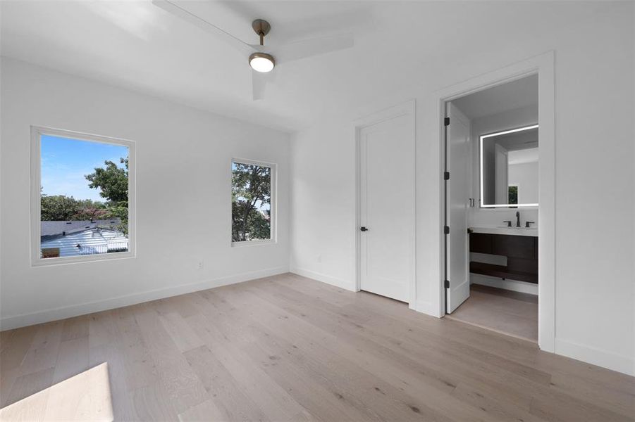 Unfurnished bedroom featuring light wood-type flooring, a ceiling fan, and connected bathroom