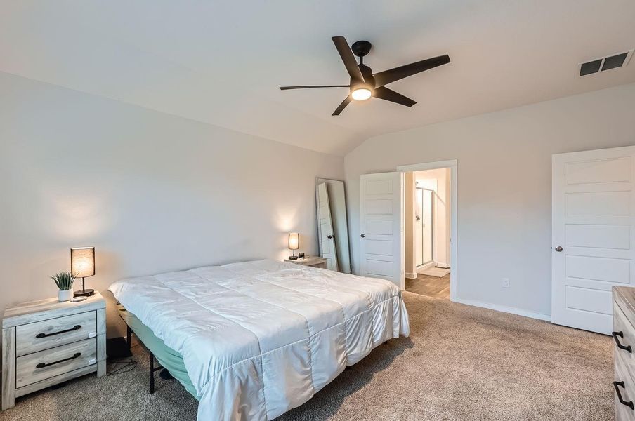 Carpeted bedroom with visible vents, baseboards, a ceiling fan, and lofted ceiling