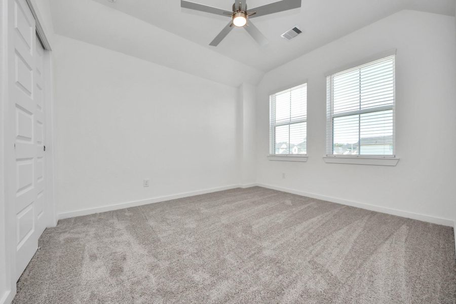 Secondary bedroom features plush carpeting, large windows that let in plenty of natural light, bright paint, and spacious closets. Sample photo of completed home with similar floor plan. Actual colors and selections may vary.