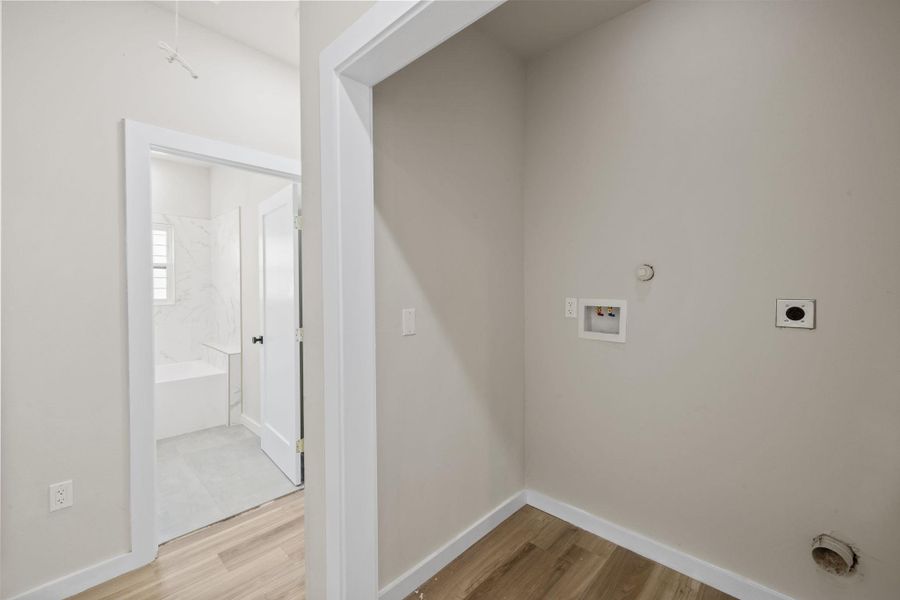Washroom featuring light wood-style flooring, washer hookup, hookup for an electric dryer, and gas dryer hookup Washroom featuring light wood-style flooring, washer hookup, hookup for an electric dryer, and gas dryer hookup