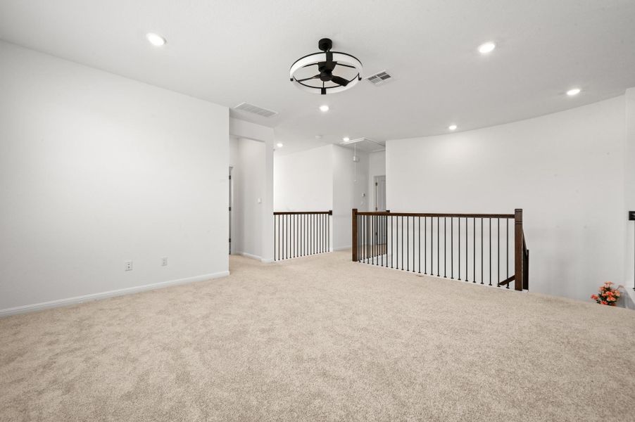 Soft carpeting underfoot pairs with recessed lighting across this versatile upper level landing.