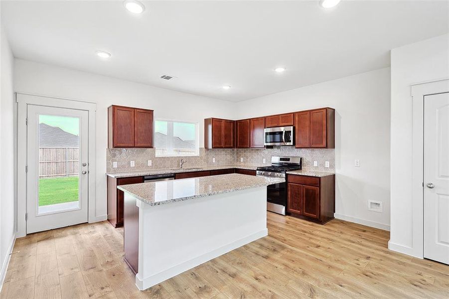 Kitchen with appliances with stainless steel finishes, a center island, light hardwood / wood-style flooring, and plenty of natural light