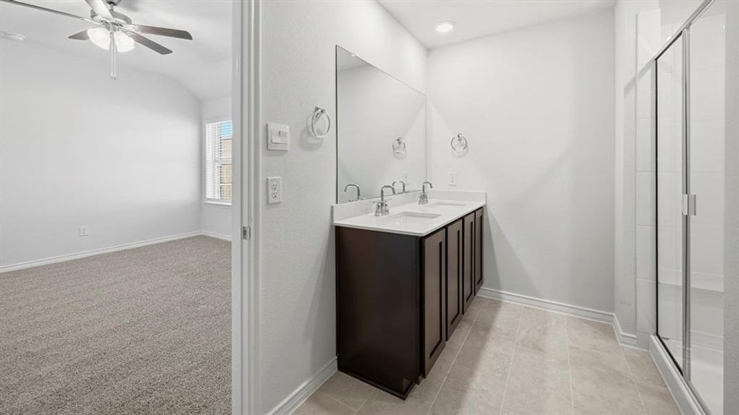 Bathroom with a shower stall, double vanity, a ceiling fan, light carpet, and lofted ceiling