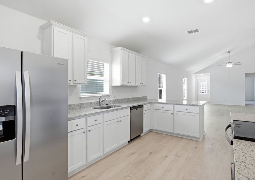 Kitchen featuring a granite island, stainless steel refrigerator, and white cabinetry with wood-look vinyl flooring. Kitchen featuring a granite island, stainless steel refrigerator, and white cabinetry with wood-look vinyl flooring.
