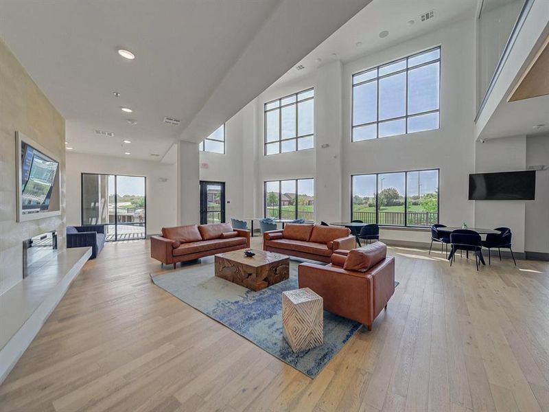 Living room featuring recessed lighting, healthy amount of natural light, light wood-style flooring, and a towering ceiling