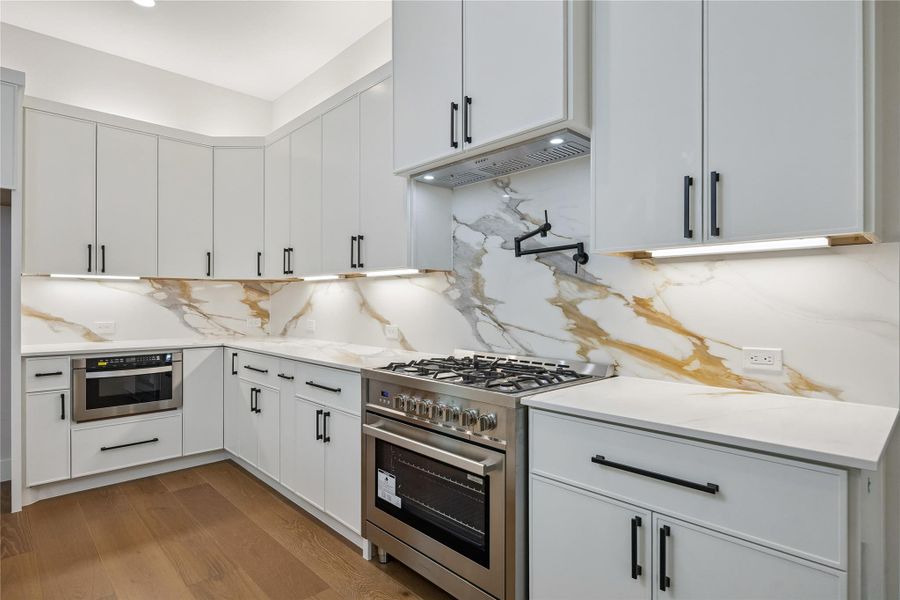 Full-height quartz backsplash detailing and professional-style appliances give the kitchen a clean, modern finish palette. Custom cabinetry and layered lighting add warmth and depth throughout the space. Full-height quartz backsplash detailing and professional-style appliances give the kitchen a clean, modern finish palette. Custom cabinetry and layered lighting add warmth and depth throughout the space.
