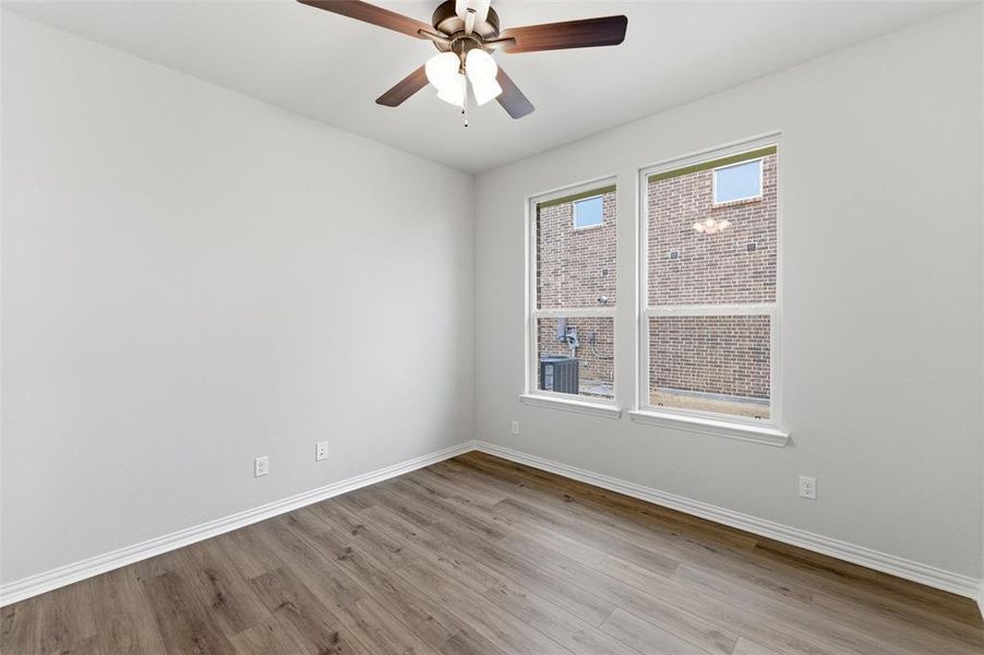 Room featuring neutral wall paint, wood-finish flooring, and white trim