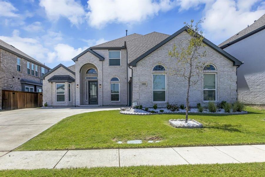 French country inspired facade with a front yard